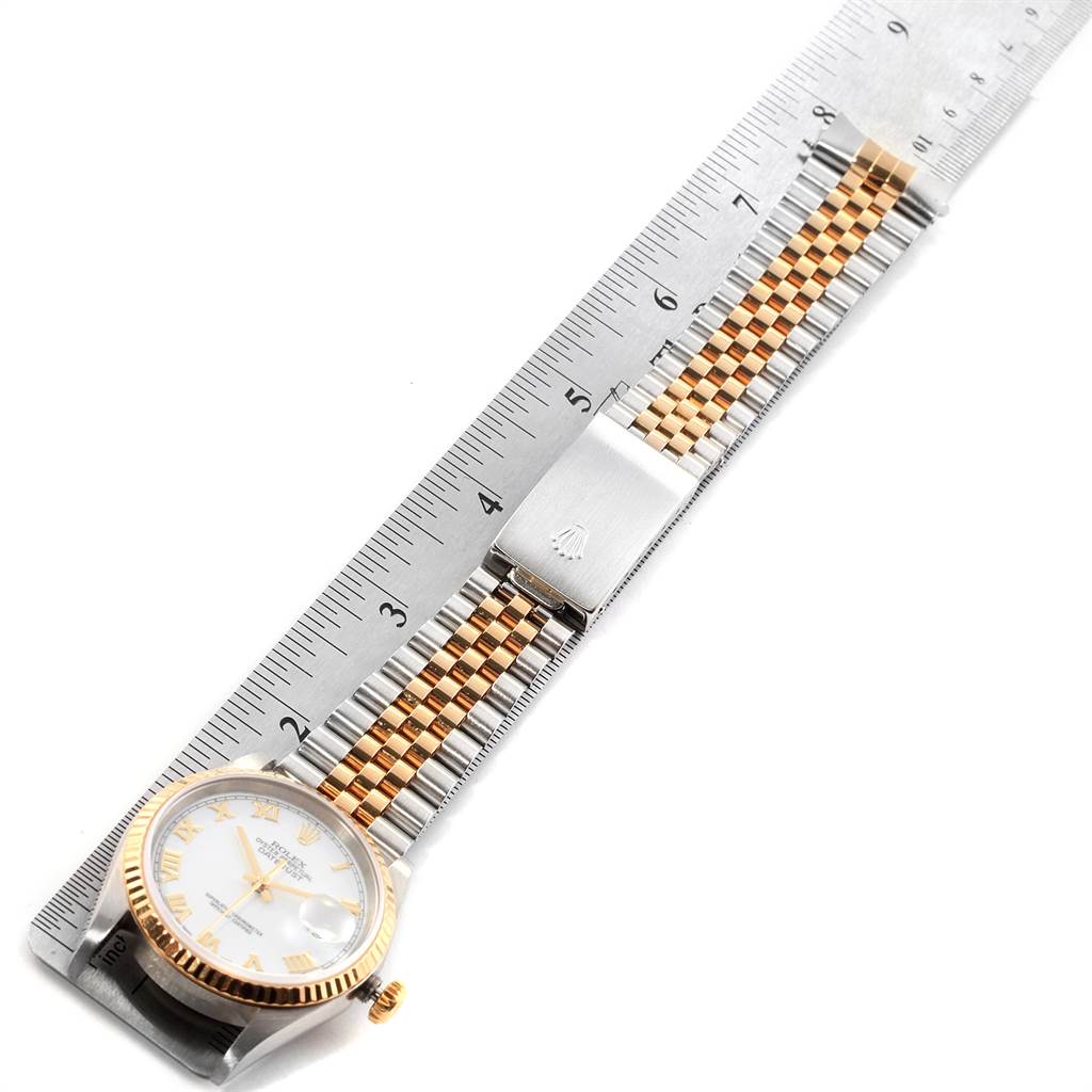 The image shows a side angle of a Rolex Datejust 16233 Men
s Steel and Gold (two tone) White Dial 16233 Men
s Steel and Gold (two tone) White Dial watch, including its face, bezel, crown, and two-tone bracelet with clasp, alongside a ruler.