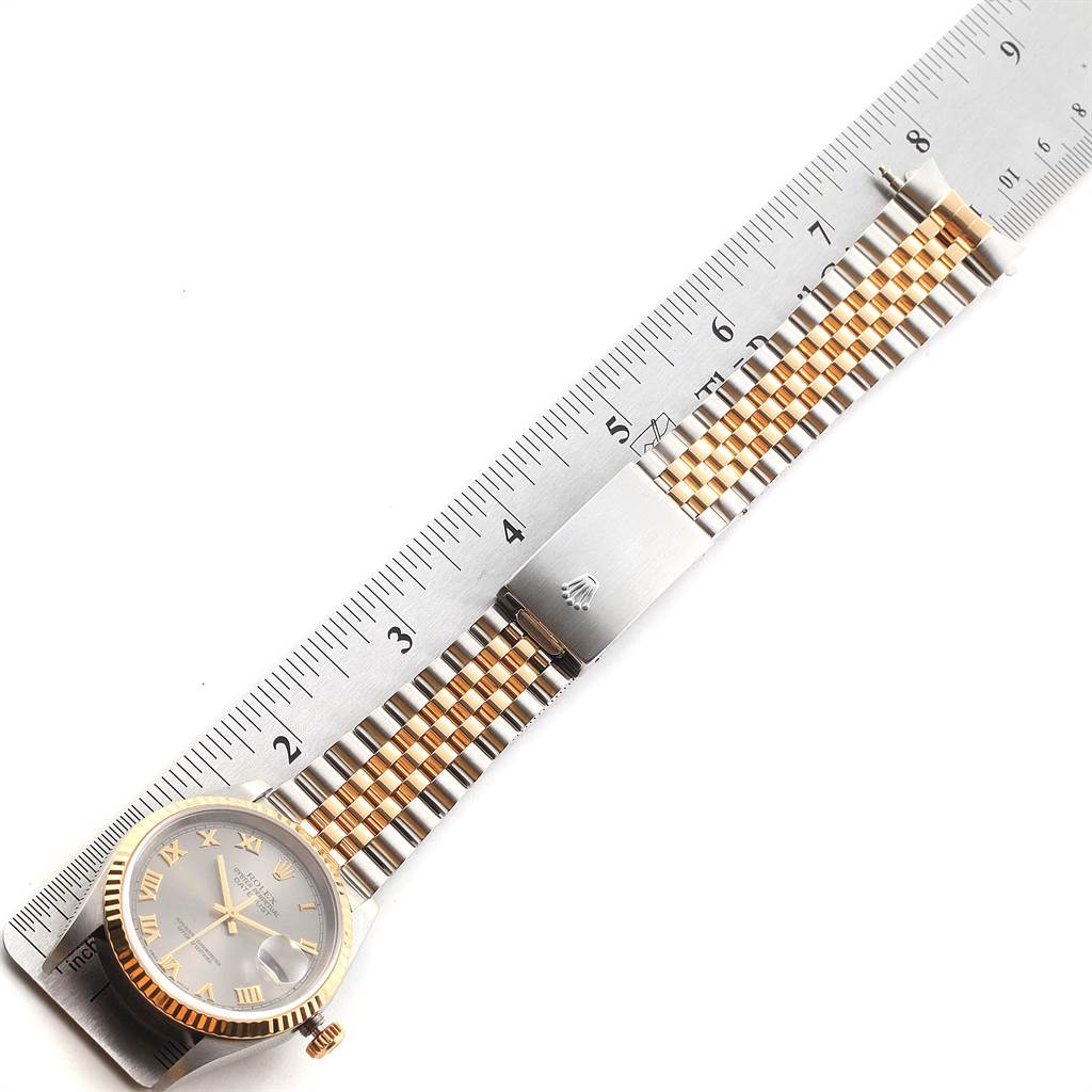 The Rolex Datejust 16233 Men's Steel and Gold (two tone) Grey Dial 16233 Men's Steel and Gold (two tone) Grey Dial watch is shown from a top-view angle, displaying its dial, case, and bracelet beside a ruler.