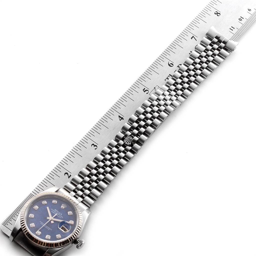 This image shows a Rolex Datejust 116234 Men's Stainless Steel Blue Dial 116234 Men's Stainless Steel Blue Dial watch laid flat alongside a ruler, highlighting the face and stainless steel bracelet.