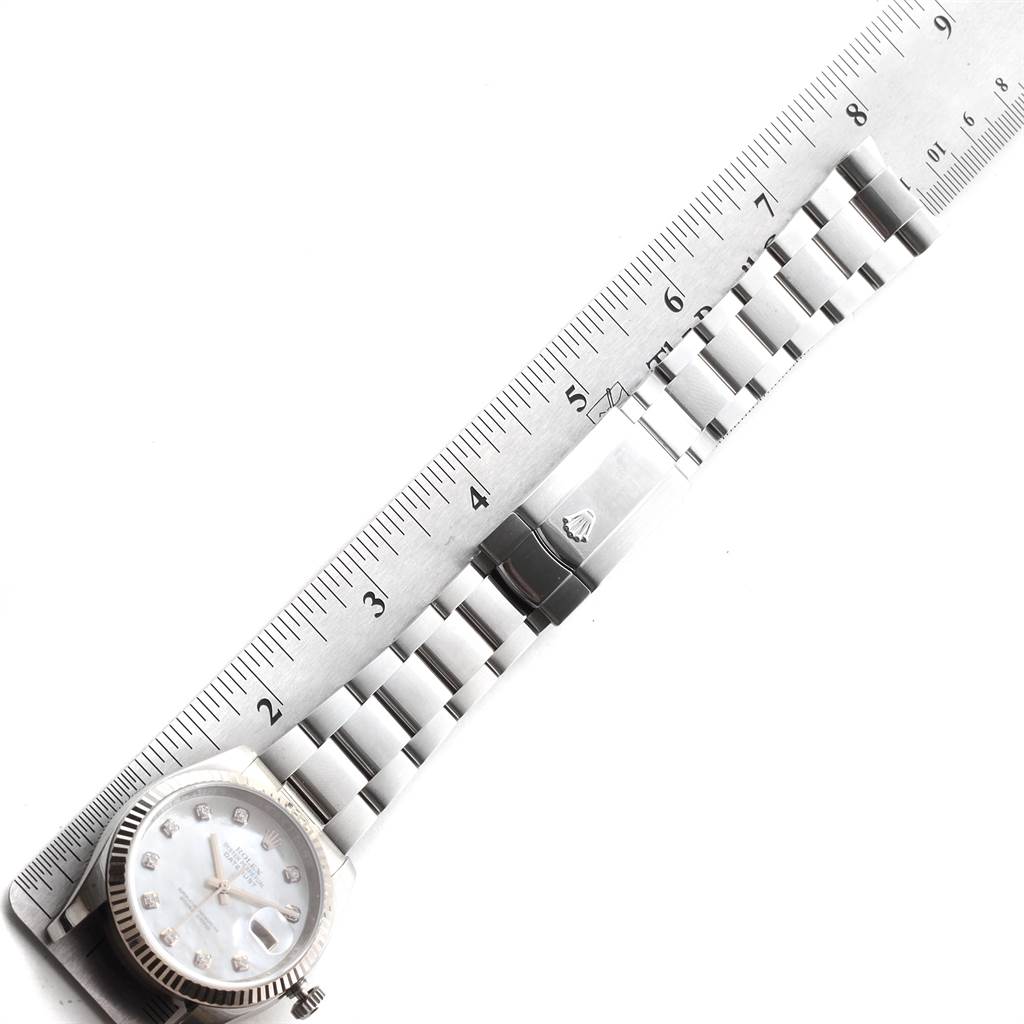 This image shows a Rolex Datejust 116234 Men's Stainless Steel Mother of Pearl Dial 116234 Men's Stainless Steel Mother of Pearl Dial watch laid flat next to a ruler, displaying the face, bracelet, and clasp.