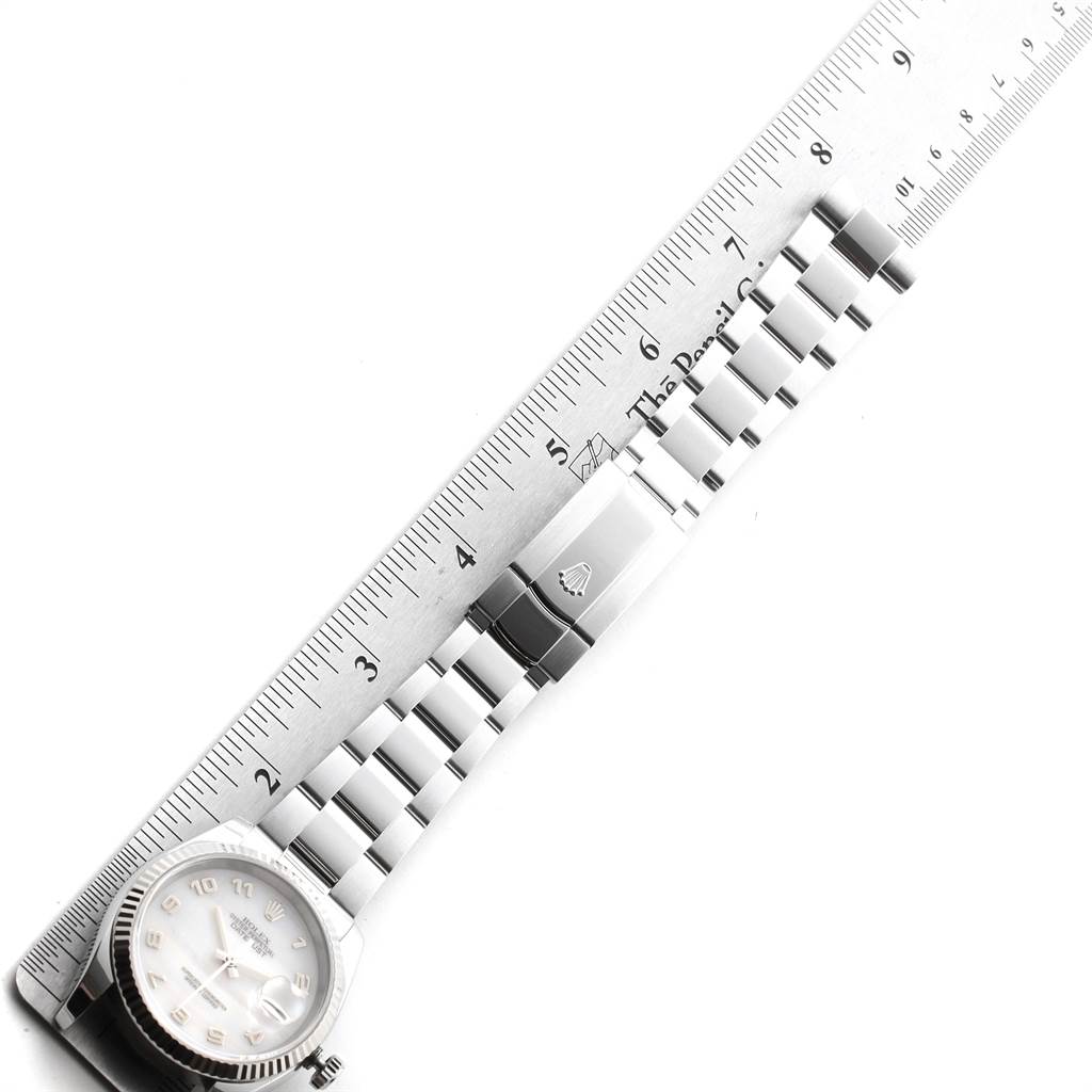 The image shows a Rolex Datejust 116234 Men
s Stainless Steel Mother of Pearl Dial 116234 Men
s Stainless Steel Mother of Pearl Dial watch laid flat alongside a ruler, highlighting its bracelet and clasp.