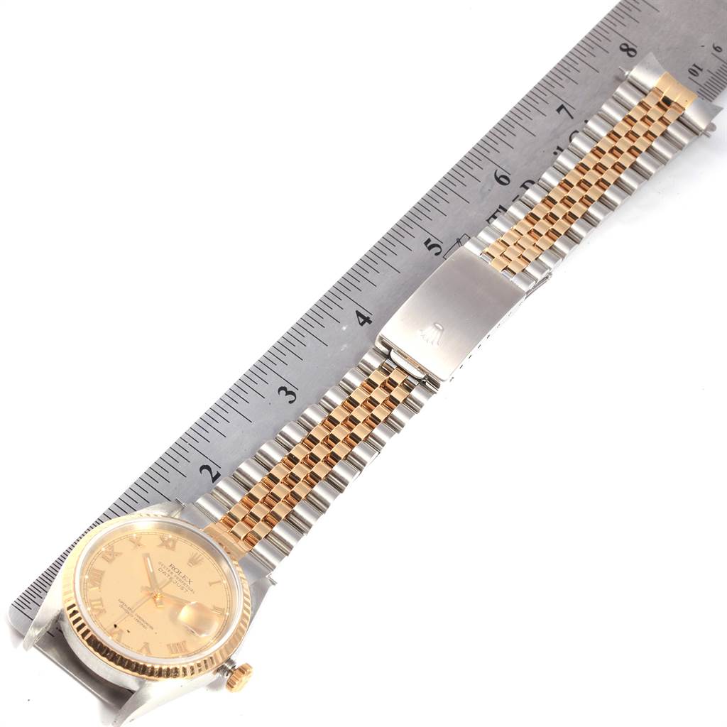 The image shows a Rolex Datejust 16233 Men's Steel and Gold (two tone) Champagne Dial 16233 Men's Steel and Gold (two tone) Champagne Dial watch from an aerial view, highlighting its face, bracelet, and clasp, alongside a ruler for scale.