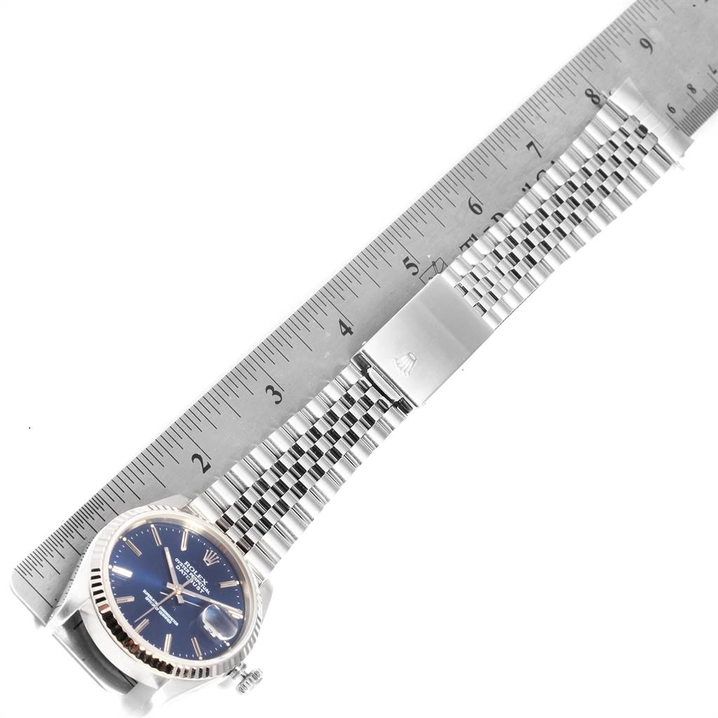 The image shows a Rolex Datejust 16234 Men's Stainless Steel Blue Dial 16234 Men's Stainless Steel Blue Dial watch laid flat next to a ruler, highlighting the face, bracelet, and clasp.