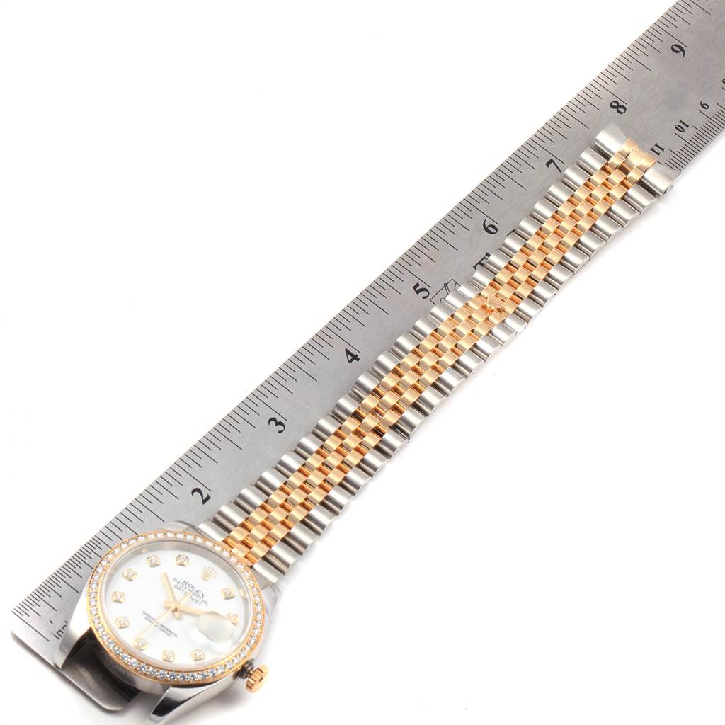 The image shows a top-down view of a Rolex Datejust 116243 Men's Stainless Steel Silver Dial 116243 Men's Stainless Steel Silver Dial watch with a ruler measuring its gold and silver bracelet.