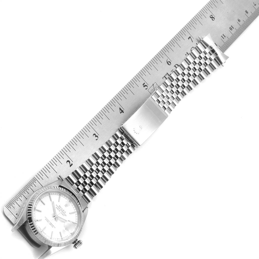 The Rolex Datejust 16234 Men's Stainless Steel White Dial 16234 Men's Stainless Steel White Dial watch is shown from an aerial angle, highlighting its face, bezel, bracelet, and the deployment clasp measured against a ruler.