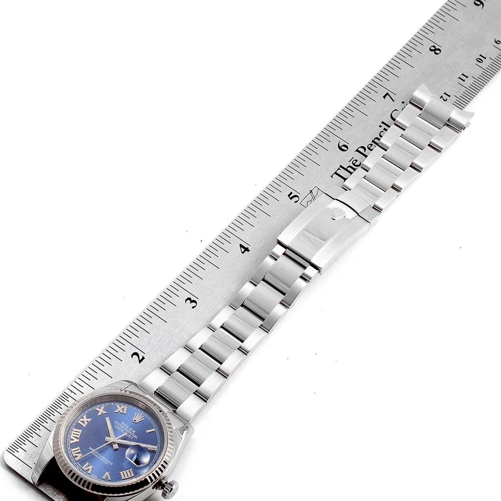 The Rolex Datejust 116234 Men
s Stainless Steel Blue Dial 116234 Men
s Stainless Steel Blue Dial watch is shown from a top-down angle, displaying its blue dial and stainless steel bracelet placed alongside a ruler.