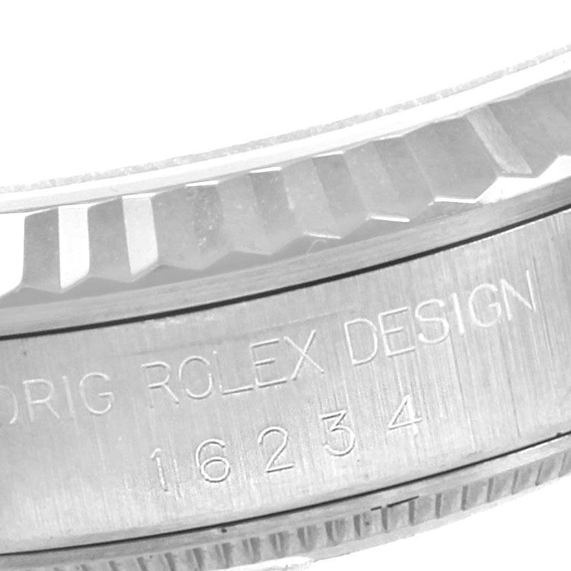 The image shows a close-up of the side of a Rolex Datejust 16234 Men's Stainless Steel Grey Dial 16234 Men's Stainless Steel Grey Dial watch, specifically its fluted bezel and engraved model number.