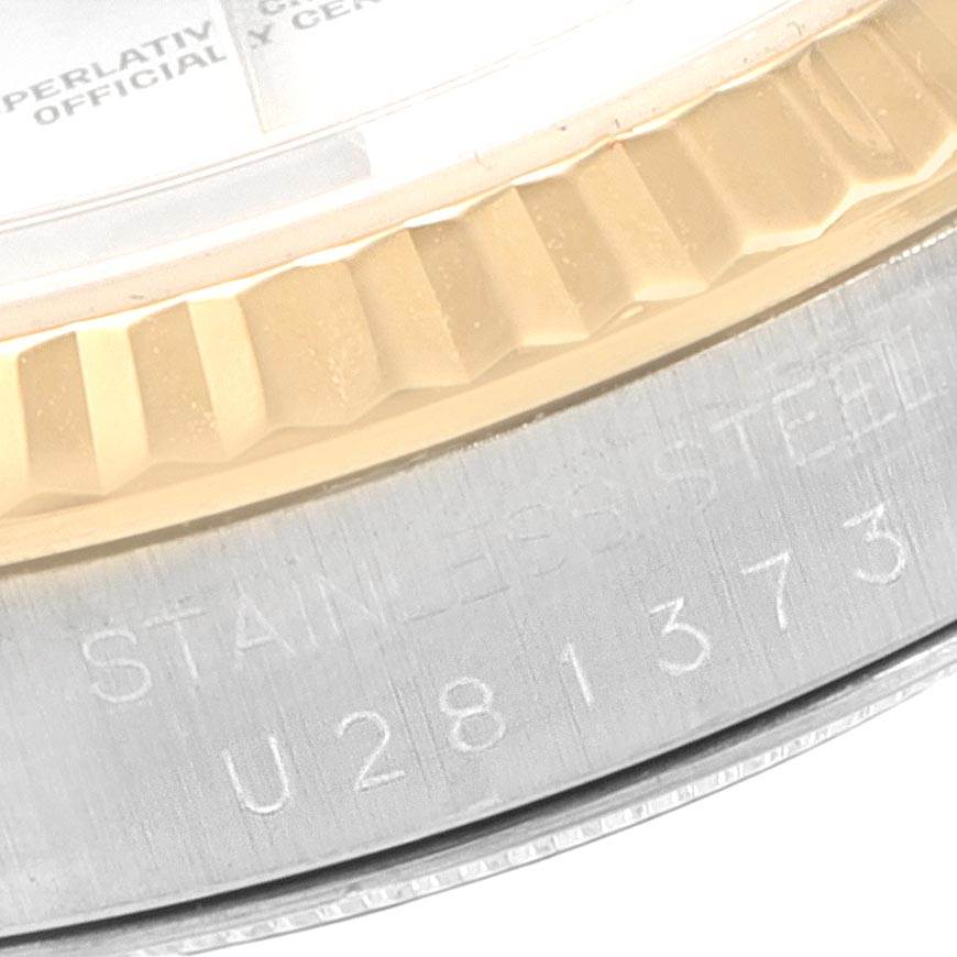 This close-up image shows the engraved serial number and part of the fluted bezel of a Rolex Datejust 16233 Men's Steel and Gold (two tone) Silver Dial 16233 Men's Steel and Gold (two tone) Silver Dial watch.