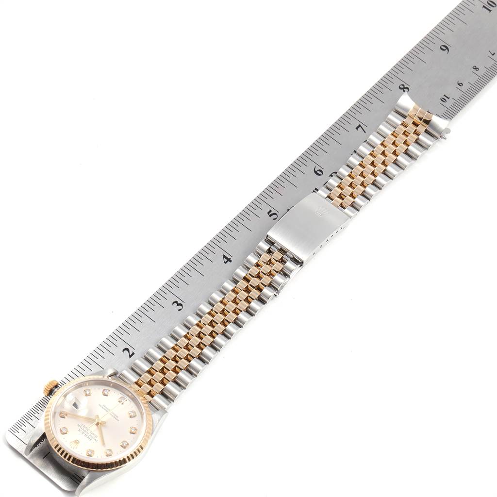 The image shows a Rolex Datejust 16233 Men's Steel and Gold (two tone) Silver Dial 16233 Men's Steel and Gold (two tone) Silver Dial watch laid flat on a measuring ruler, highlighting its dial and two-tone bracelet.