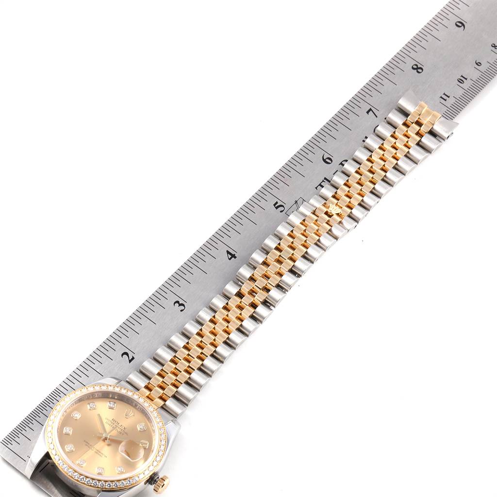 The image shows a Rolex Datejust 116243 Men
s Steel and Gold (two tone) Champagne Dial 116243 Men
s Steel and Gold (two tone) Champagne Dial watch laid next to a ruler, displaying part of the watch face and the full bracelet.