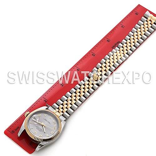 The Rolex Datejust 116233-SRJ Men
s Stainless Steel Silver Dial 116233-SRJ Men
s Stainless Steel Silver Dial watch is shown lying flat next to a red ruler, displaying the face and the full bracelet.