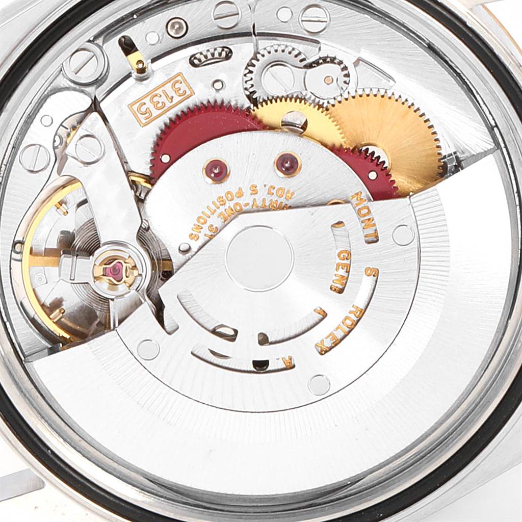 The image shows the intricate inner workings of a Rolex Datejust 16233 Men's Steel and Gold (two tone) White Dial 16233 Men's Steel and Gold (two tone) White Dial watch, focusing on its gears and rotor mechanism.