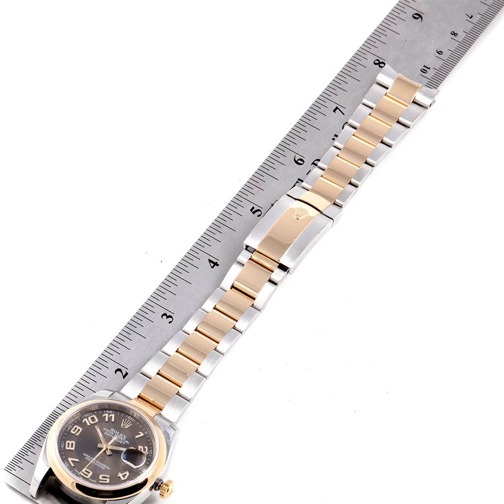The Rolex Datejust 116203 Men
s Stainless Steel Brown Dial 116203 Men
s Stainless Steel Brown Dial watch is shown from the side at a slight angle, highlighting its face, bracelet, and clasp with a ruler for scale.