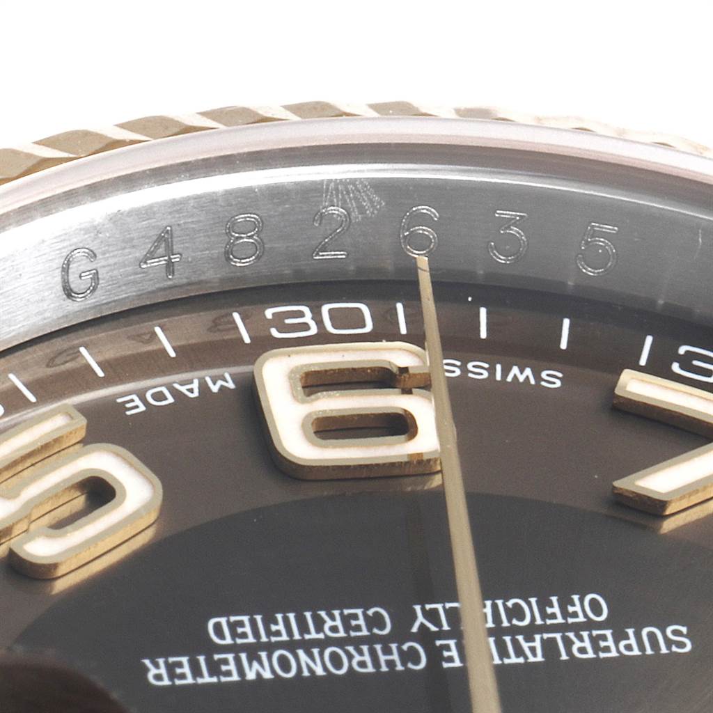 Close-up of the Rolex Datejust 116233 Men's Steel and Gold (two tone) Brown Dial 116233 Men's Steel and Gold (two tone) Brown Dial watch showing part of the dial, bezel, and Rolex logo engraving.
