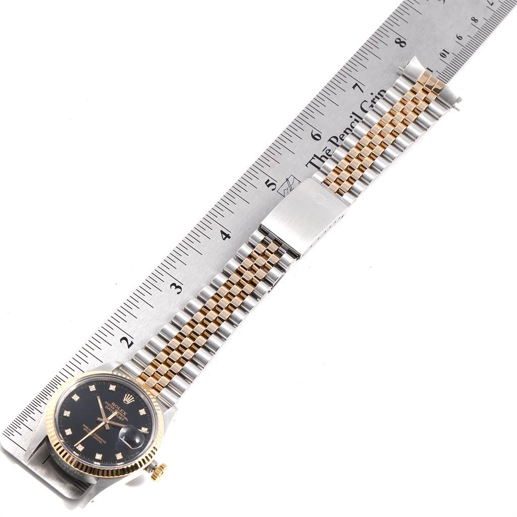 The Rolex Datejust 16013 Men's Stainless Steel Black Dial 16013 Men's Stainless Steel Black Dial watch is shown from a top-down angle, displaying its face, bezel, and bracelet against a ruler for scale.