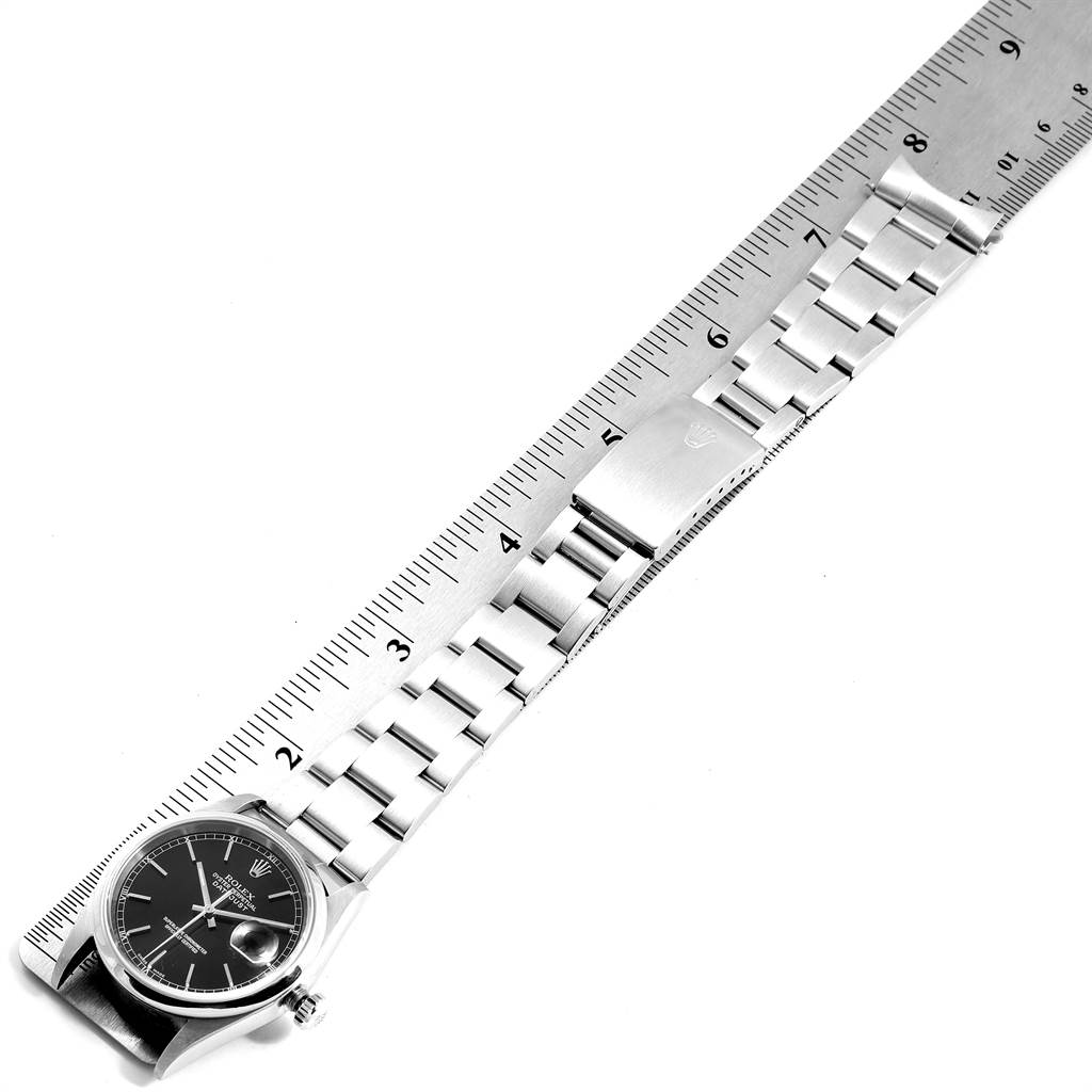 The image shows a full view of the Rolex Datejust 16200 Men's Stainless Steel Black Dial 16200 Men's Stainless Steel Black Dial watch laid adjacent to a ruler, displaying its case, dial, and band.