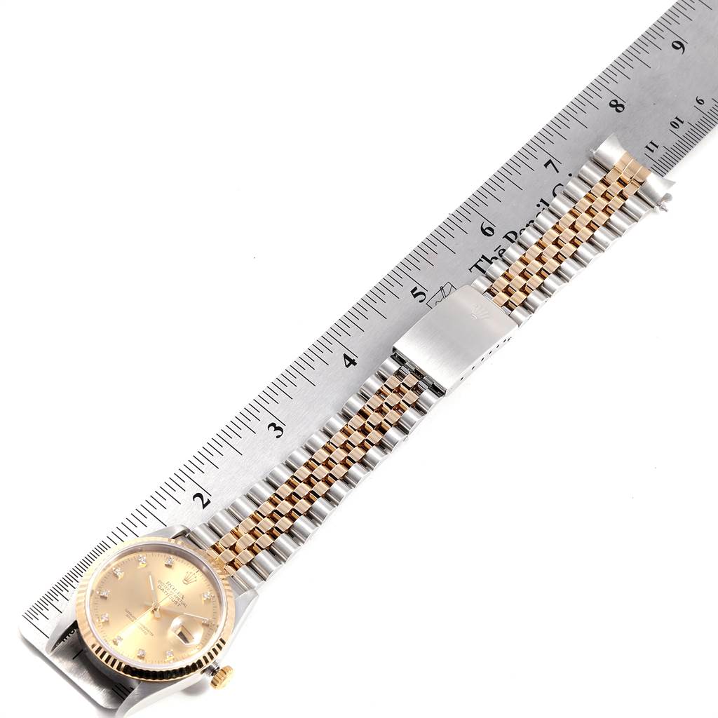This image shows a Rolex Datejust 16233 Men
s Steel and Gold (two tone) Champagne Dial 16233 Men
s Steel and Gold (two tone) Champagne Dial watch with its face and two-tone bracelet stretched out beside a ruler for measurement.