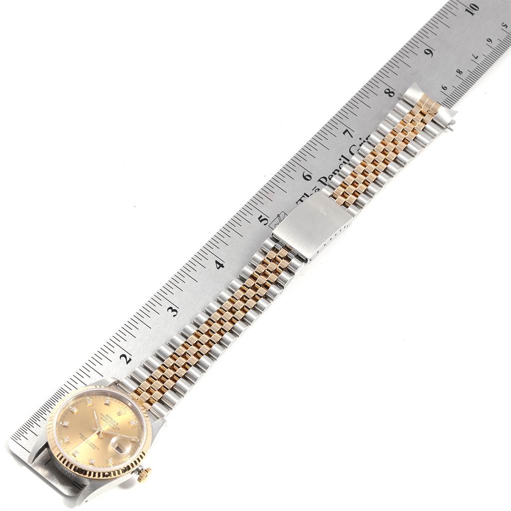 The Rolex Datejust 16233 Men
s Steel and Gold (two tone) Champagne Dial 16233 Men
s Steel and Gold (two tone) Champagne Dial watch is shown from above, displaying its face, bezel, and two-tone bracelet next to a ruler.