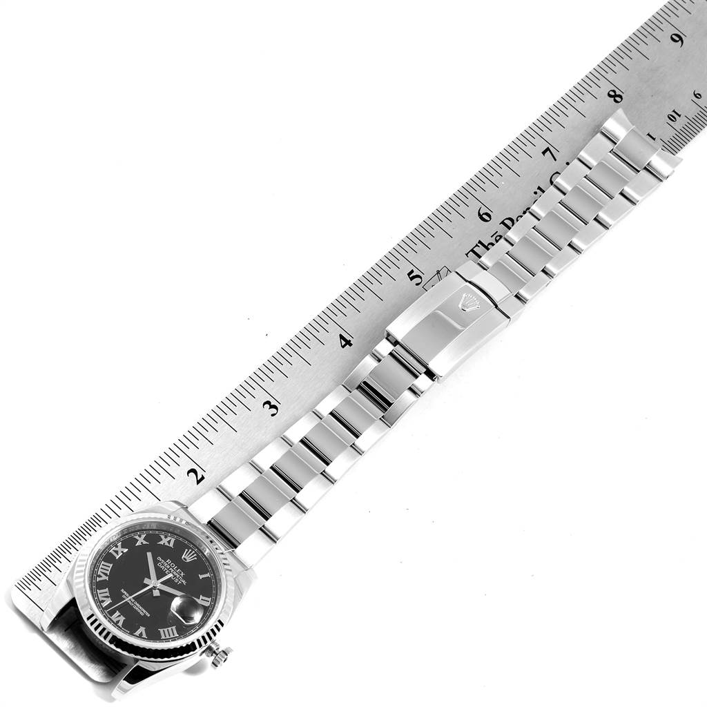 The image shows a Rolex Datejust 116234 Men's Stainless Steel Black Dial 116234 Men's Stainless Steel Black Dial watch laid flat alongside a ruler, displaying the face, bracelet, and clasp.