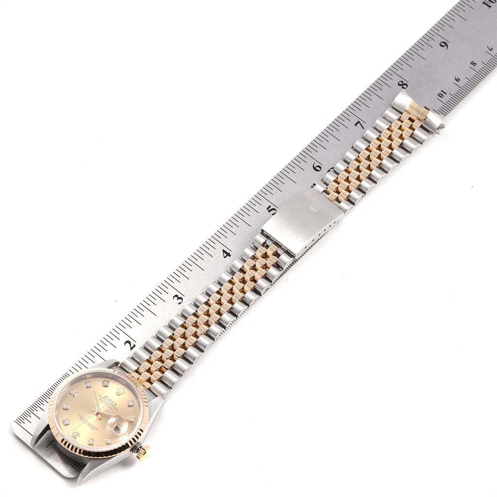 This image shows a Rolex Datejust 16233 Men
s Steel and Gold (two tone) Champagne Dial 16233 Men
s Steel and Gold (two tone) Champagne Dial watch laying flat with a partially visible jubilee bracelet, next to a ruler for scale.