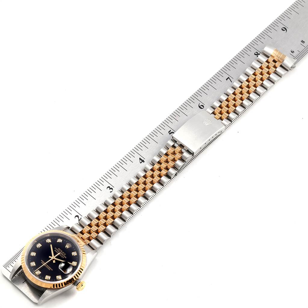 This image shows the Rolex Datejust 16233 Men
s Steel and Gold (two tone) Black Dial 16233 Men
s Steel and Gold (two tone) Black Dial watch laid flat with the face, bracelet, and clasp all visible, next to a ruler.