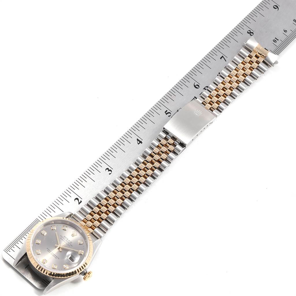 The Rolex Datejust 16233 Men's Steel and Gold (two tone) Silver Dial 16233 Men's Steel and Gold (two tone) Silver Dial watch is shown from the top, displaying the full dial and the entire two-tone bracelet against a ruler.