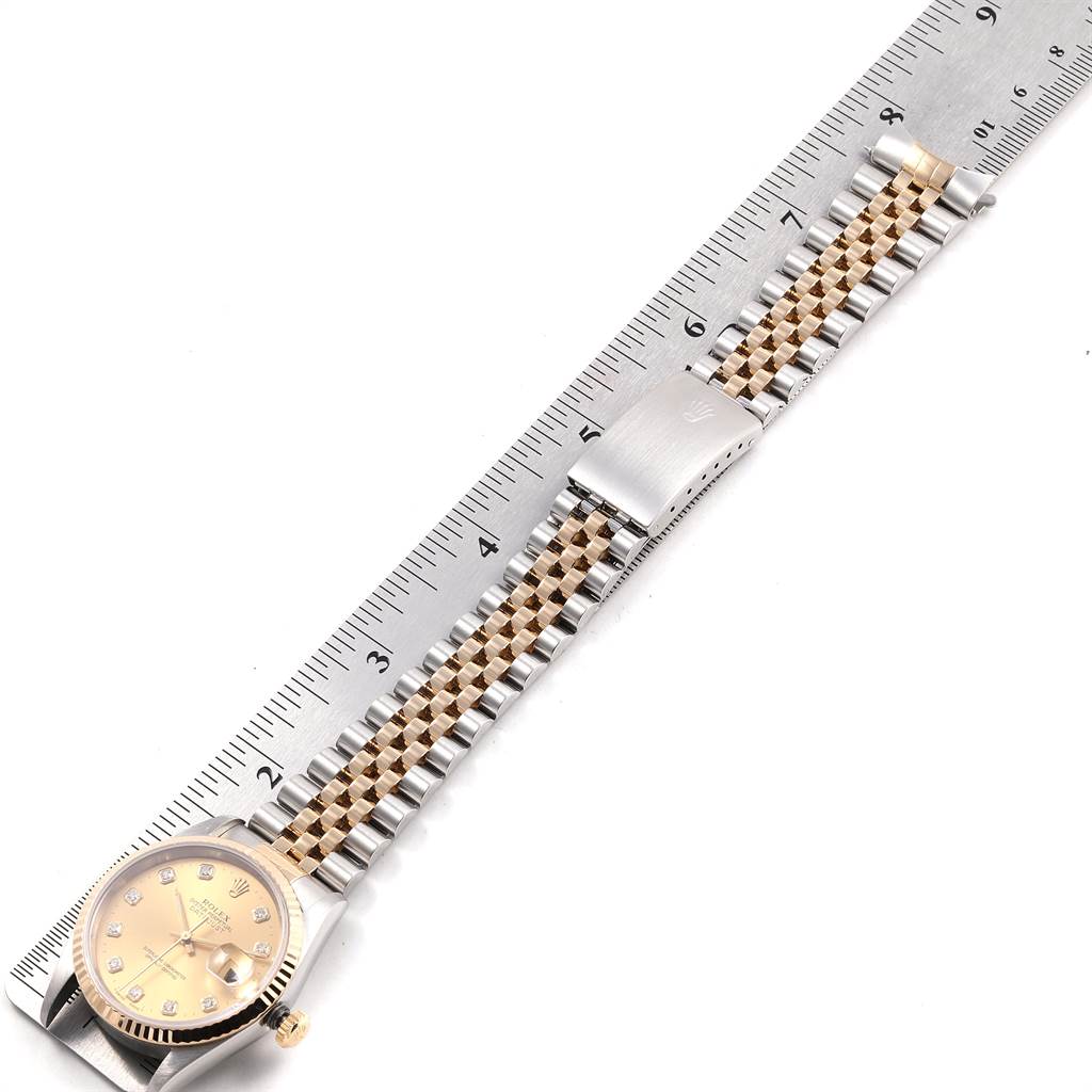 The image shows a Rolex Datejust 16233 Men
s Steel and Gold (two tone) Champagne Dial 16233 Men
s Steel and Gold (two tone) Champagne Dial watch laid flat with its bracelet stretched out next to a ruler for measurement.