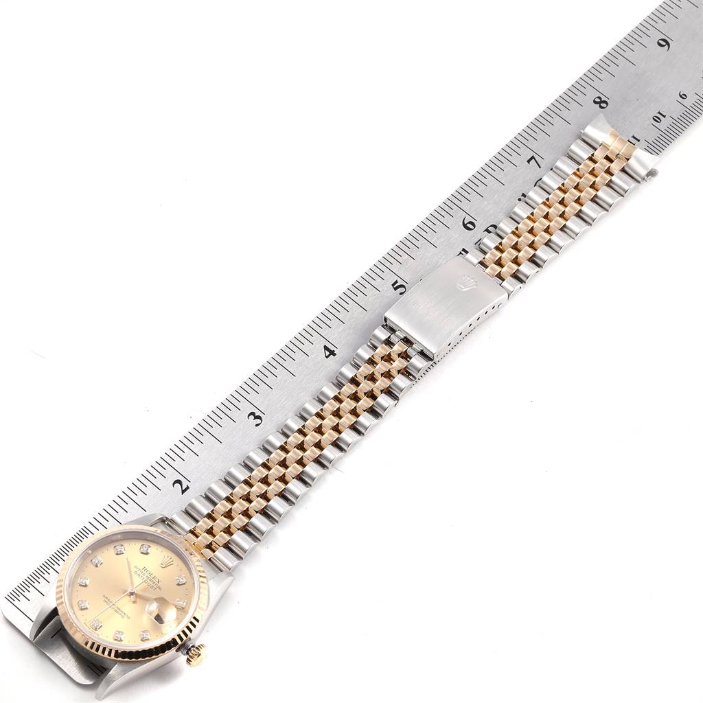 The image shows a Rolex Datejust 16233 Men
s Steel and Gold (two tone) Champagne Dial 16233 Men
s Steel and Gold (two tone) Champagne Dial watch laid flat, displaying its face, bracelet, and clasp next to a ruler.