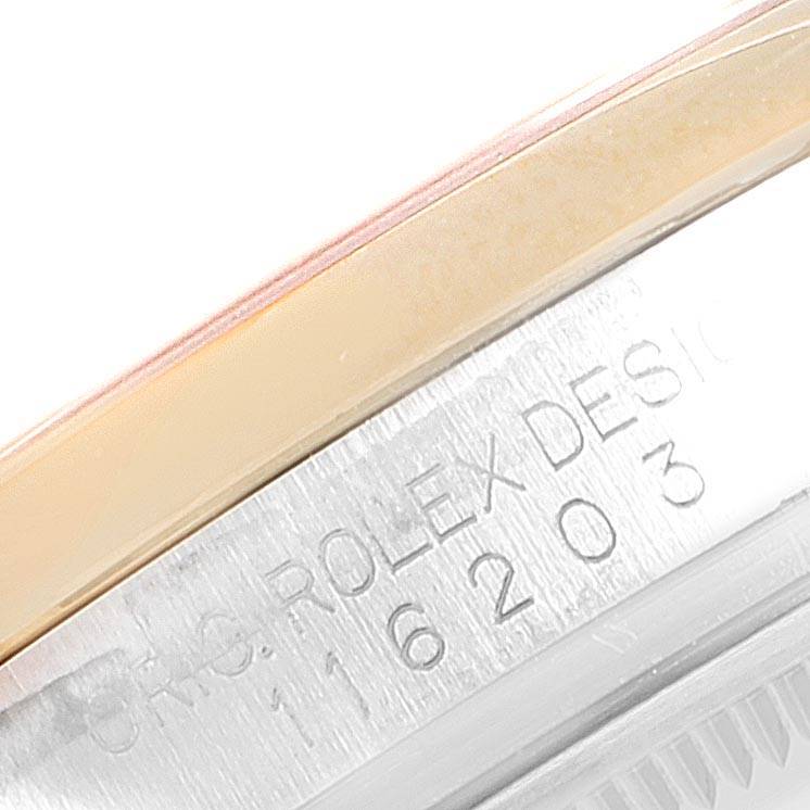 This close-up image of a Rolex Datejust 116203 Men
s Steel and Gold (two tone) Blue Dial 116203 Men
s Steel and Gold (two tone) Blue Dial watch shows the engraved side of the case and a portion of the bezel.