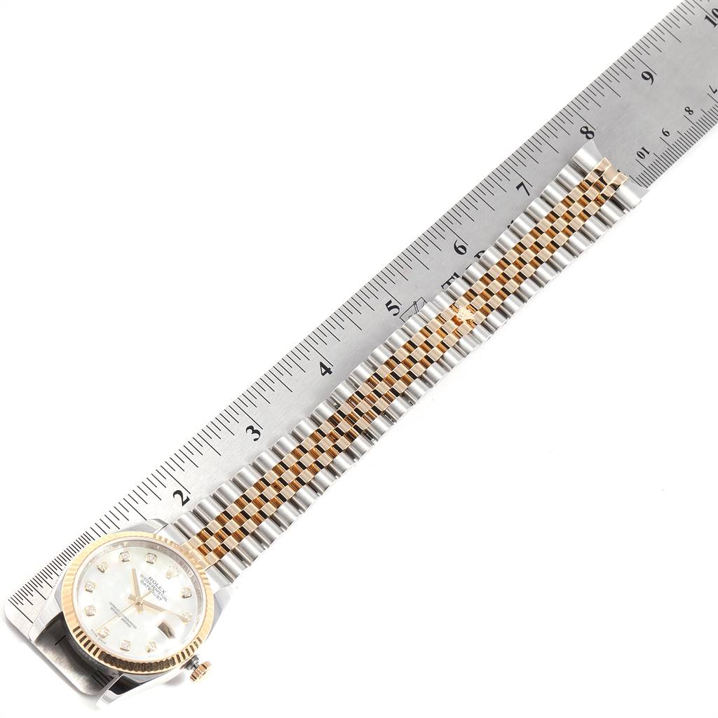 The image shows a side view of a Rolex Datejust 116233 Men
s Stainless Steel Mother of Pearl Dial 116233 Men
s Stainless Steel Mother of Pearl Dial watch and its two-tone bracelet alongside a measuring ruler.