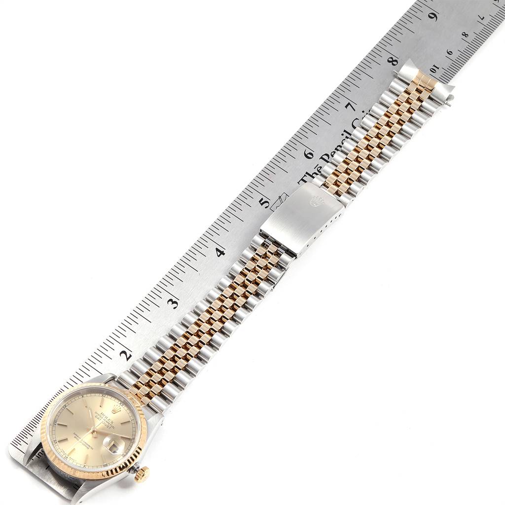 The image shows a Rolex Datejust 16233 Men's Steel and Gold (two tone) Champagne Dial 16233 Men's Steel and Gold (two tone) Champagne Dial watch lying flat, aligned with a ruler, displaying its gold dial and two-tone bracelet.