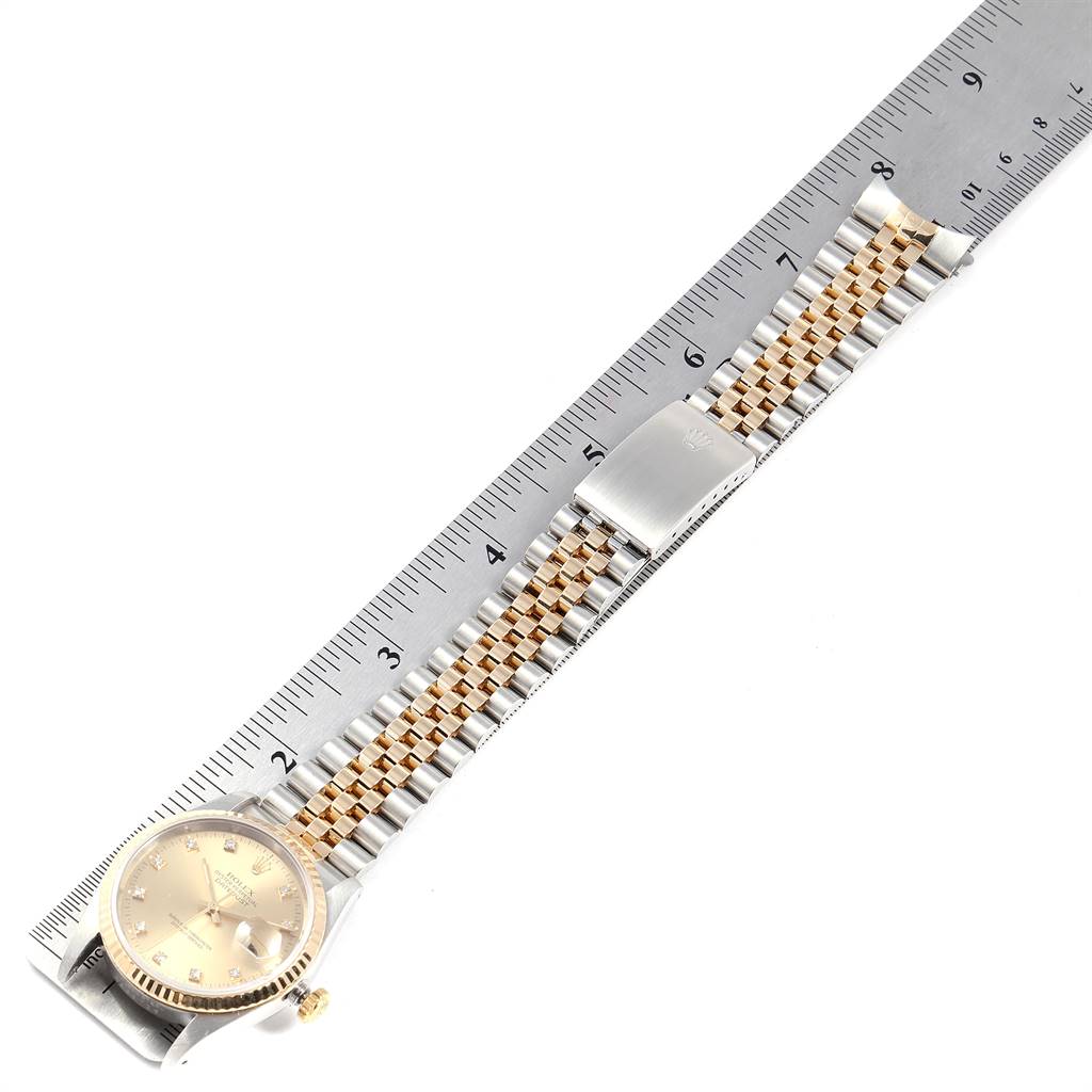 The Rolex Datejust 16233 Men
s Steel and Gold (two tone) Champagne Dial 16233 Men
s Steel and Gold (two tone) Champagne Dial watch is shown flat with its full bracelet and clasp visible, alongside a ruler for measurement.