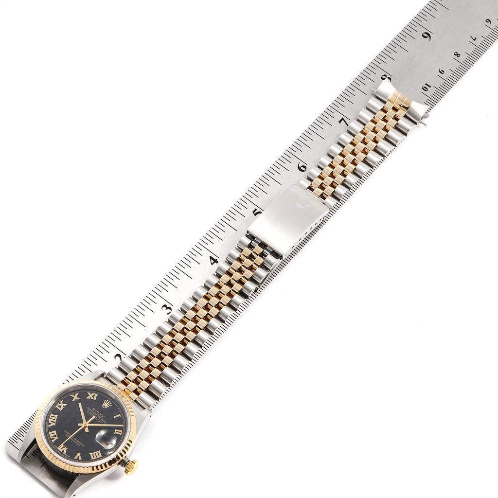 The image shows a Rolex Datejust 16233 Men
s Steel and Gold (two tone) Black Dial 16233 Men
s Steel and Gold (two tone) Black Dial watch laid flat with its band against a ruler, displaying its face and bracelet.