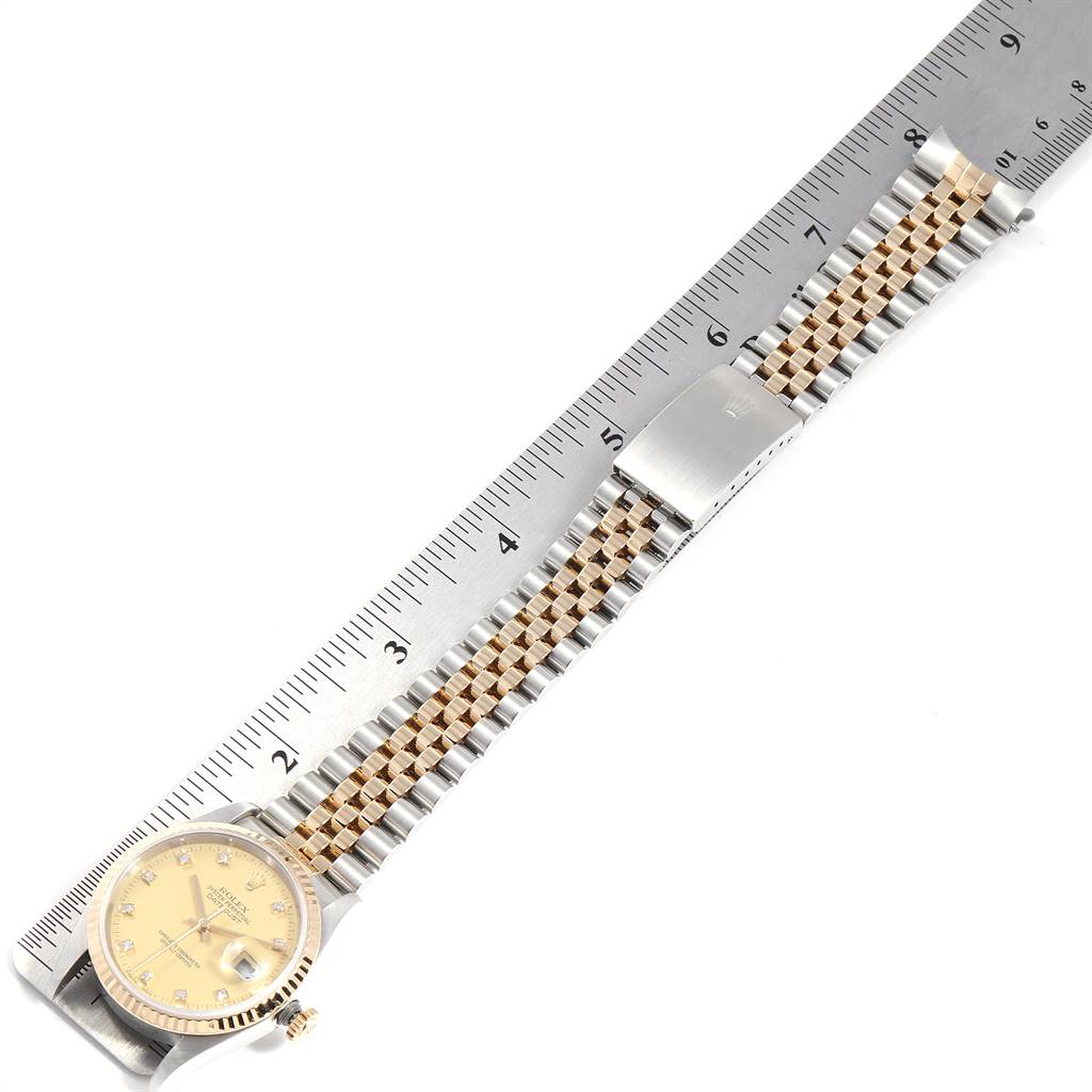 The Rolex Datejust 16233 Men's Steel and Gold (two tone) Champagne Dial 16233 Men's Steel and Gold (two tone) Champagne Dial watch is shown flat with a ruler, highlighting its bracelet and dial from a top-down angle.