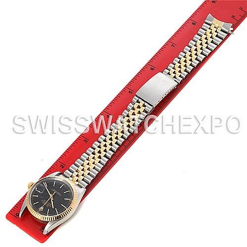 This image shows a top-down view of a Rolex Datejust 16013 Men's Stainless Steel Black Dial 16013 Men's Stainless Steel Black Dial watch with a two-tone bracelet and a dark dial, placed over a red ruler.