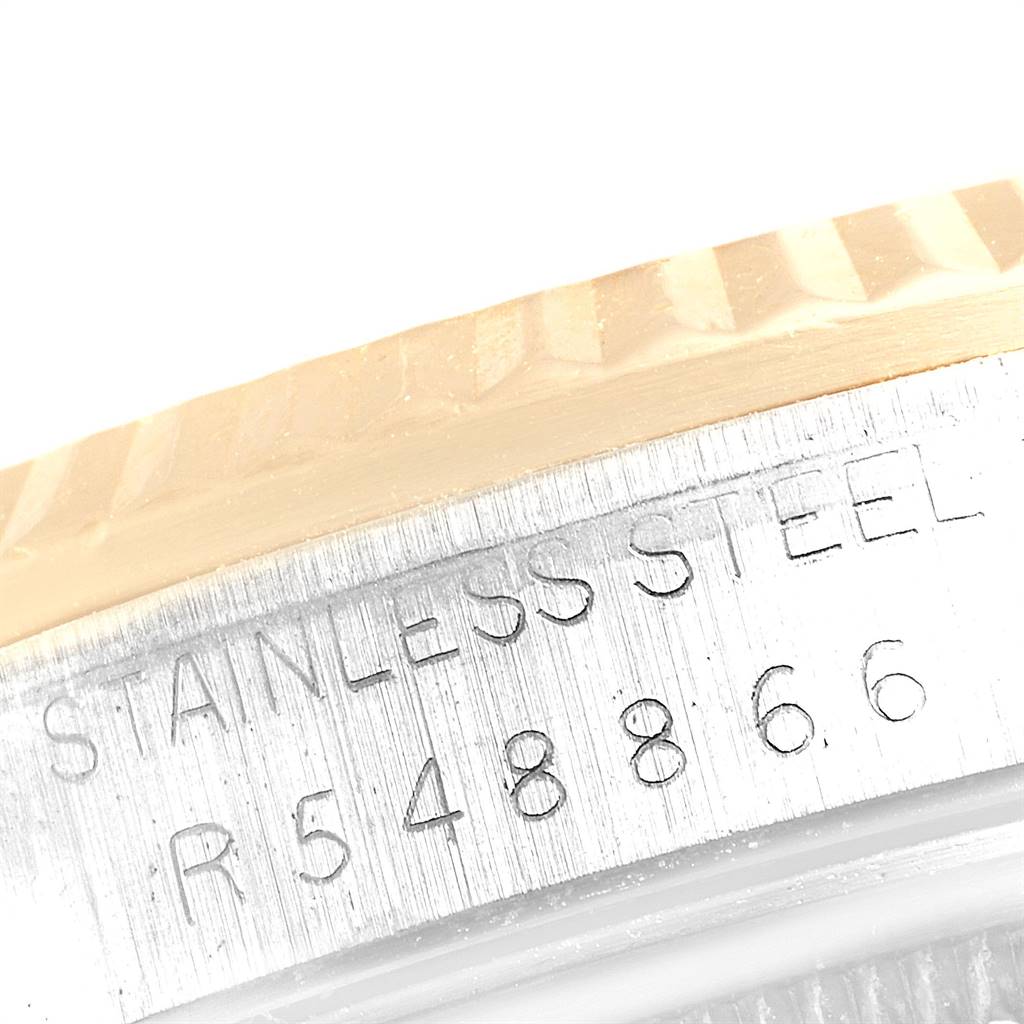 This close-up image shows the side of the case and part of the bezel of the Rolex Datejust 16233 Men
s Steel and Gold (two tone) Blue Dial 16233 Men
s Steel and Gold (two tone) Blue Dial, featuring engraved text.