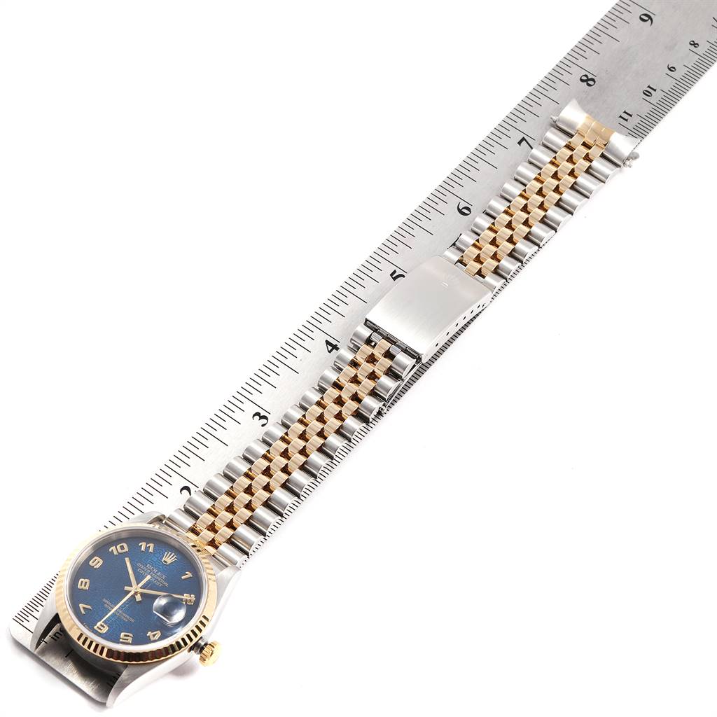 The Rolex Datejust 16233 Men
s Steel and Gold (two tone) Blue Dial 16233 Men
s Steel and Gold (two tone) Blue Dial watch is shown flat, with a close-up view of the face, strap, and clasp alongside a ruler.