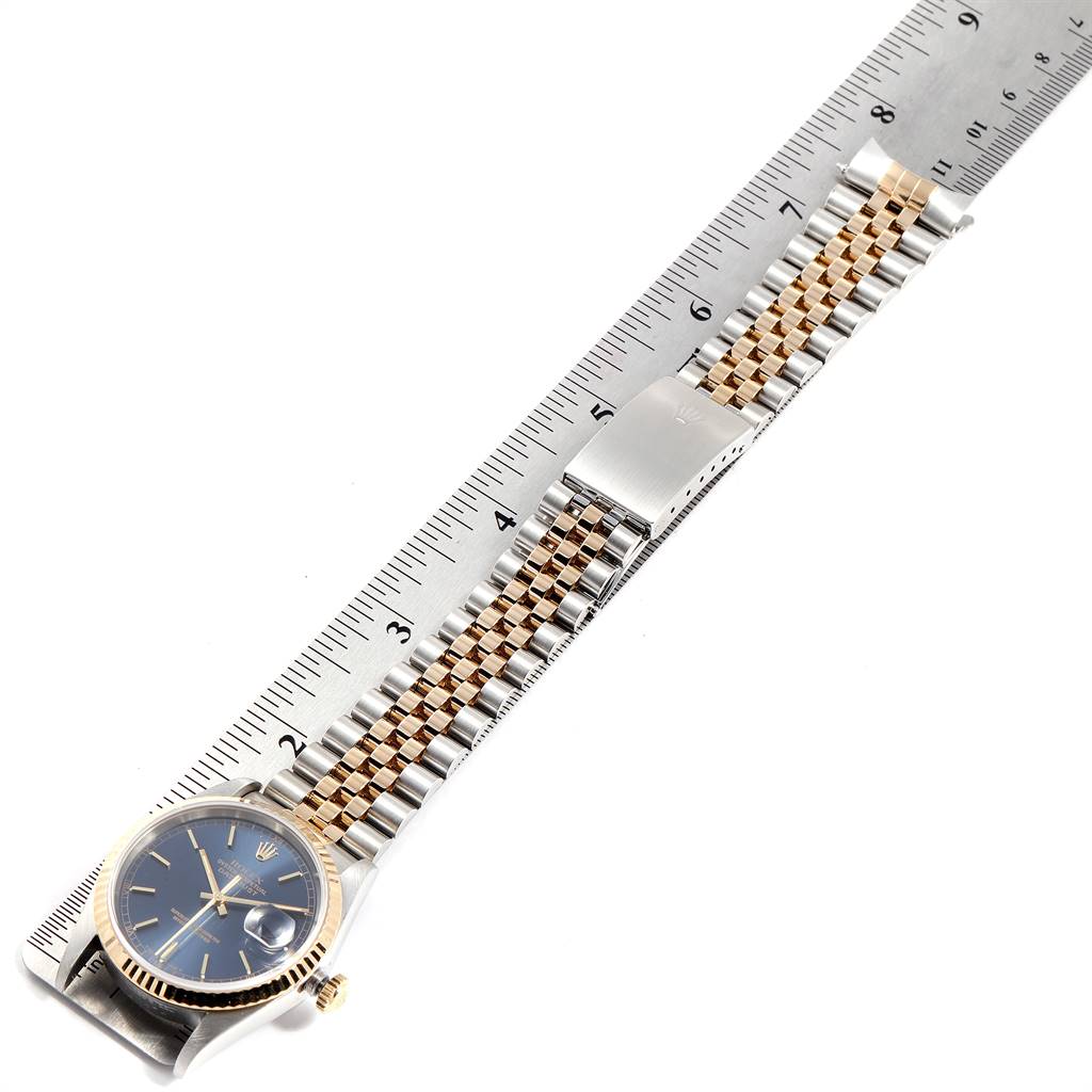 The Rolex Datejust 16233 Men's Steel and Gold (two tone) Blue Dial 16233 Men's Steel and Gold (two tone) Blue Dial watch is shown lying flat with its stainless steel and gold bracelet, accompanied by a ruler for scale.