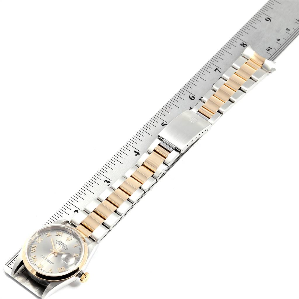 The Rolex Datejust 16203 Men's Steel and Gold (two tone) Grey Dial 16203 Men's Steel and Gold (two tone) Grey Dial watch band is aligned with a ruler, showing the bracelet and part of the watch face at an angle.