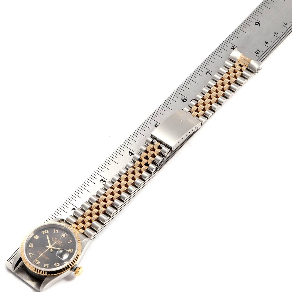 The image shows a top-down view of a Rolex Datejust 16233 Men's Steel and Gold (two tone) Grey Dial 16233 Men's Steel and Gold (two tone) Grey Dial watch placed next to a ruler, highlighting the band and watch face.