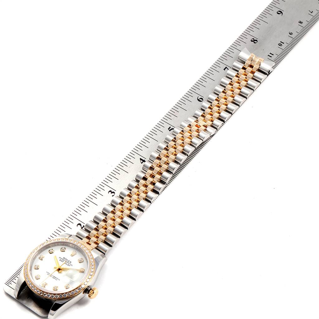 The Rolex Datejust 116243 Men's Steel and Gold (two tone) White Dial 116243 Men's Steel and Gold (two tone) White Dial watch is displayed flat with its bracelet extended next to a ruler for measurement.