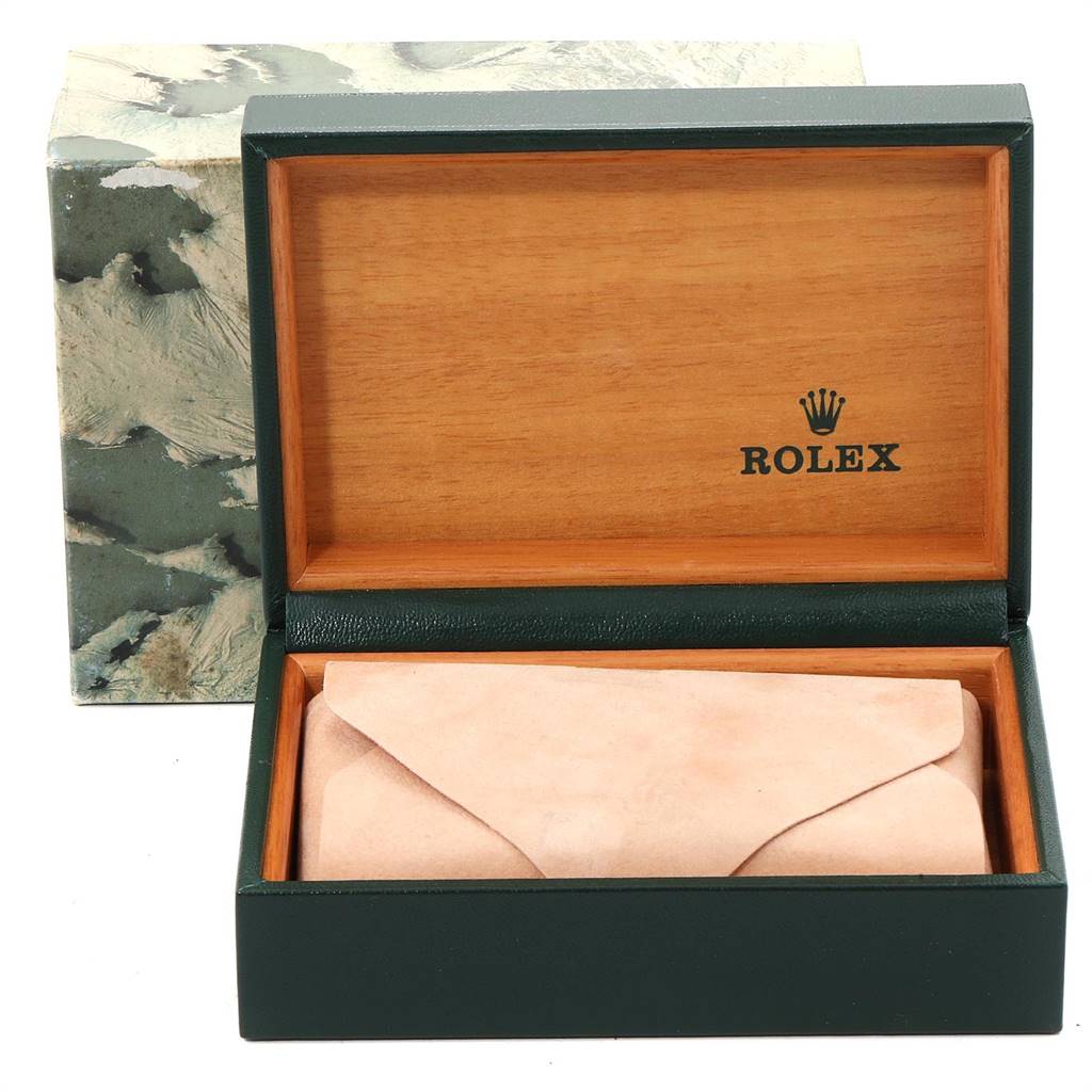 The image shows an open Rolex box, displaying the interior and a beige pouch, with the Rolex branding visible.