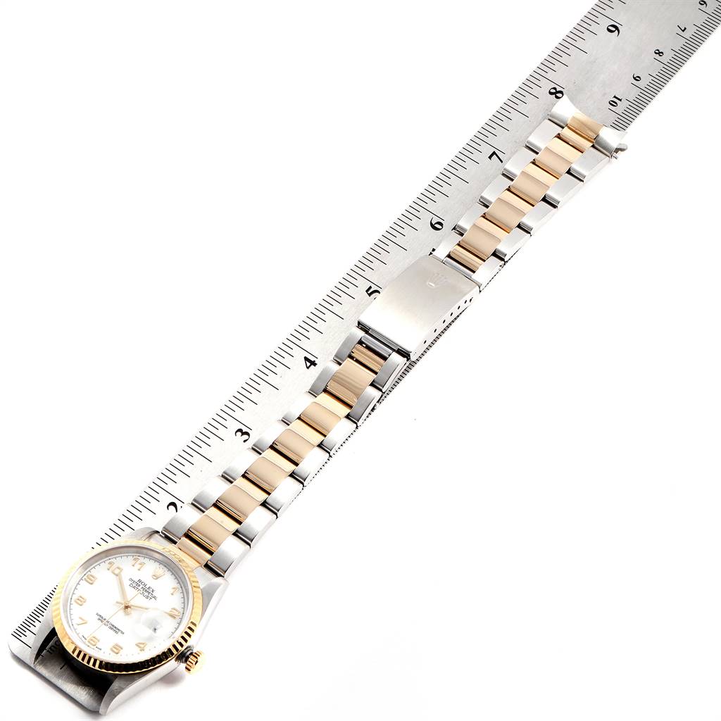 This image shows a Rolex Datejust 16233 Men's Steel and Gold (two tone) White Dial 16233 Men's Steel and Gold (two tone) White Dial watch laid flat along a ruler, displaying the face and bracelet.