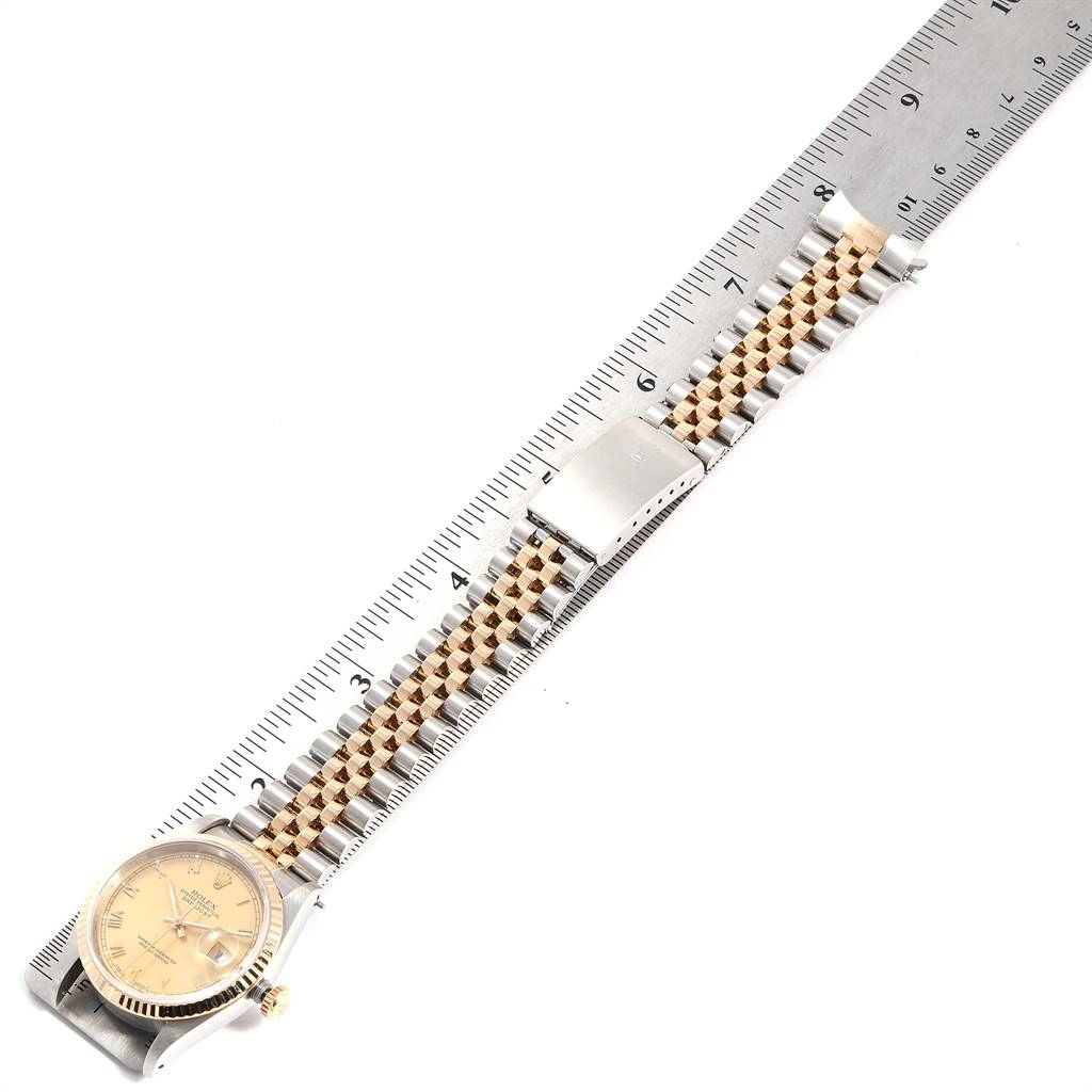 The Rolex Datejust 16233 Men
s Steel and Gold (two tone) Champagne Dial 16233 Men
s Steel and Gold (two tone) Champagne Dial watch is displayed flat with a focus on the bracelet and clasp, placed next to a ruler for scale.