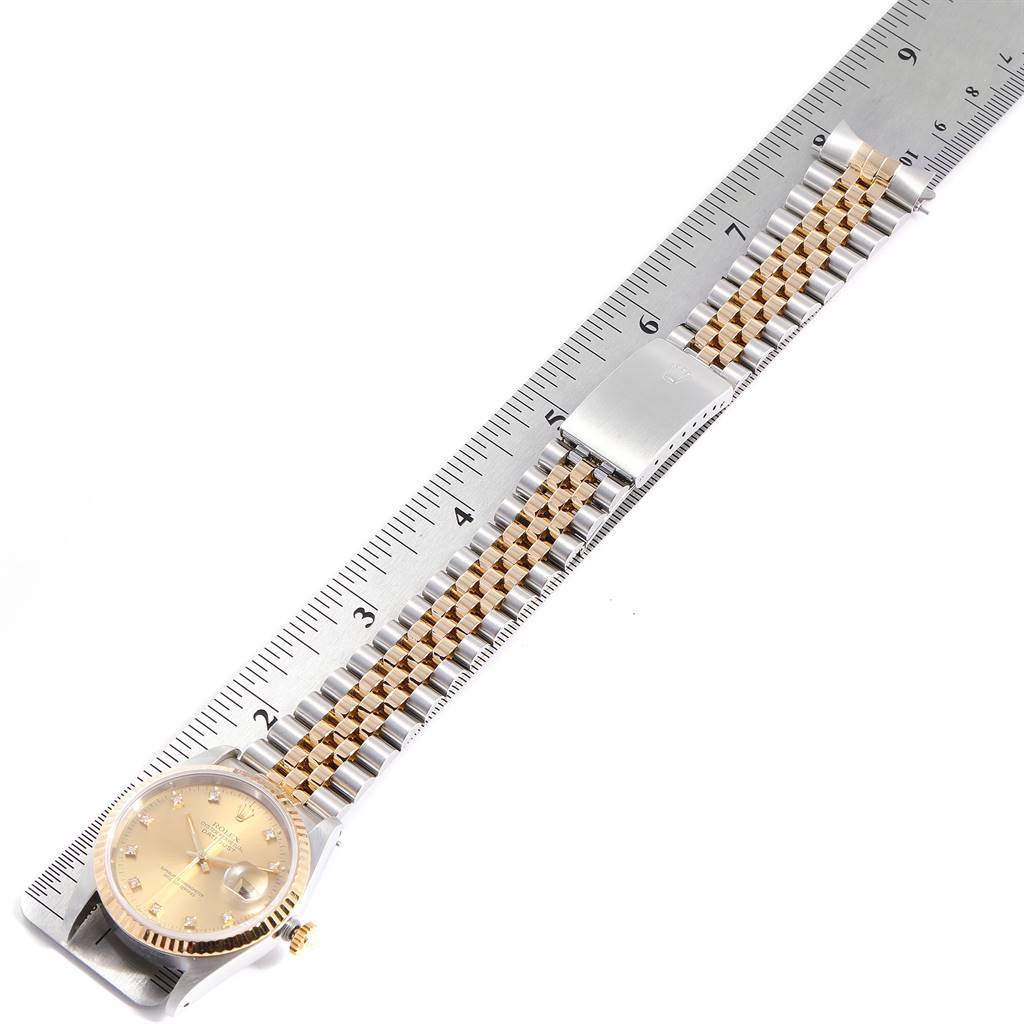 This image shows a Rolex Datejust 16233 Men
s Steel and Gold (two tone) Champagne Dial 16233 Men
s Steel and Gold (two tone) Champagne Dial watch placed next to a ruler, highlighting its strap and face in a top-down angle.