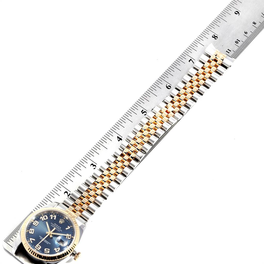 The image shows the Rolex Datejust 116233 Men
s Steel and Gold (two tone) Blue Dial 116233 Men
s Steel and Gold (two tone) Blue Dial watch laid flat next to a ruler, highlighting the blue dial and two-tone bracelet.