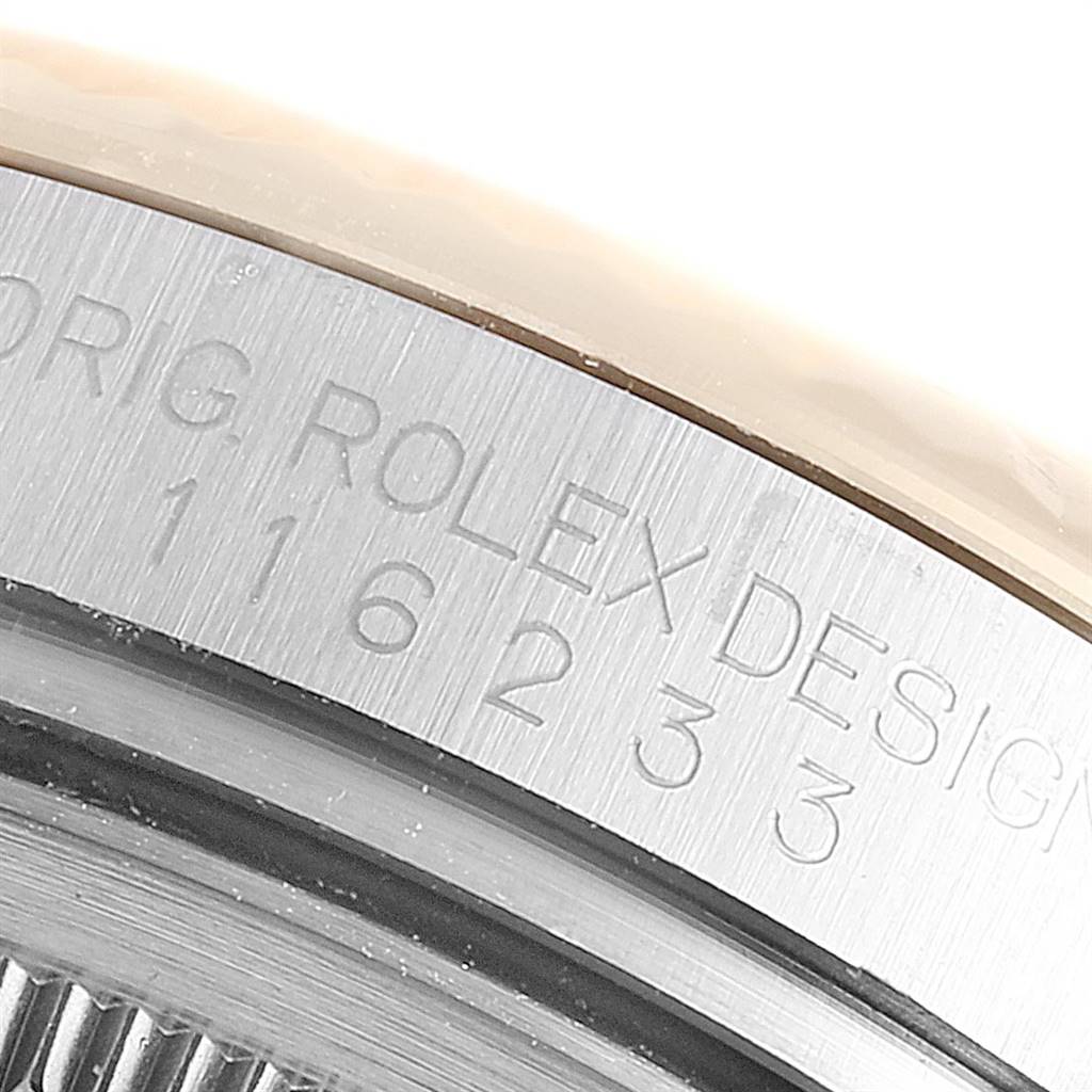 The image shows a close-up of the side of the case of a Rolex Datejust 116233 Men's Stainless Steel Grey Dial 116233 Men's Stainless Steel Grey Dial watch, depicting engravings.
