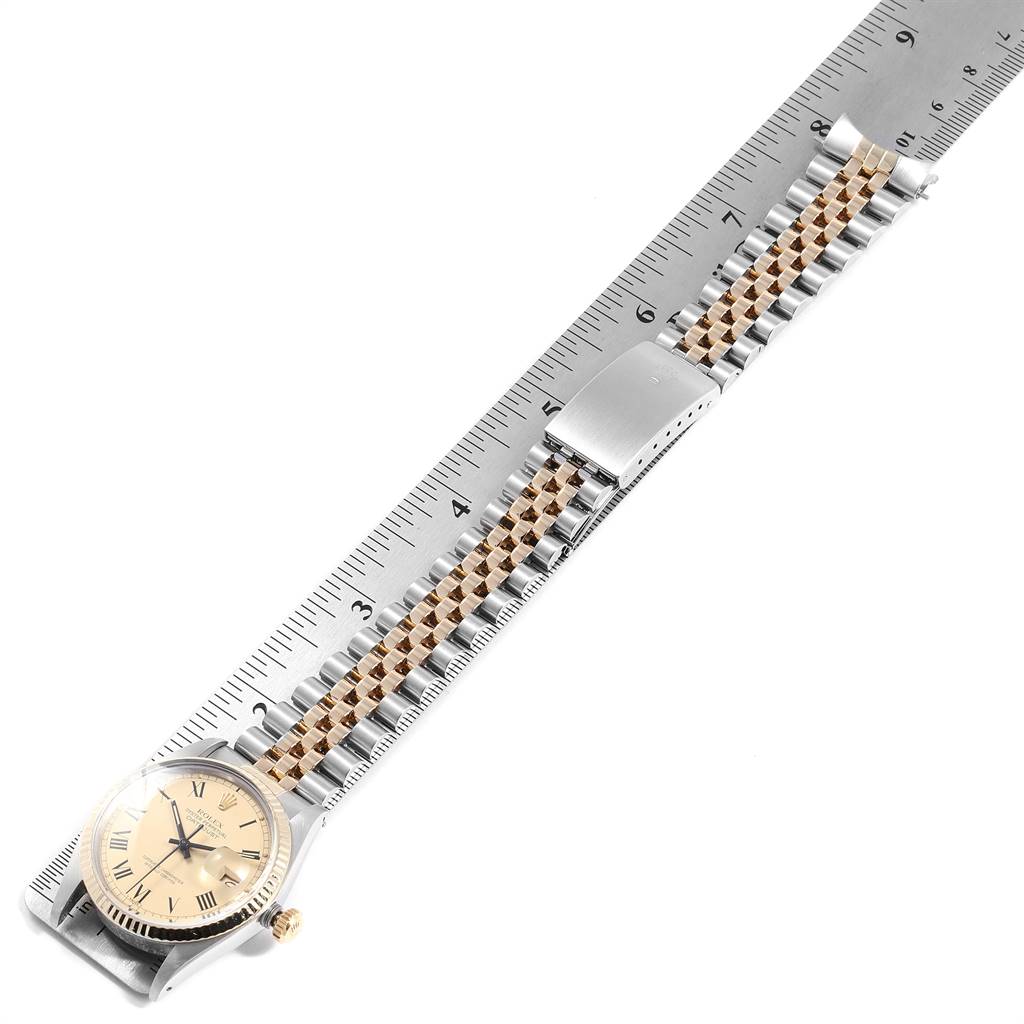 The image shows a Rolex Datejust 16013 Men
s Stainless Steel Champagne Dial 16013 Men
s Stainless Steel Champagne Dial watch laid flat on a ruler, highlighting its face, bezel, and two-tone bracelet.