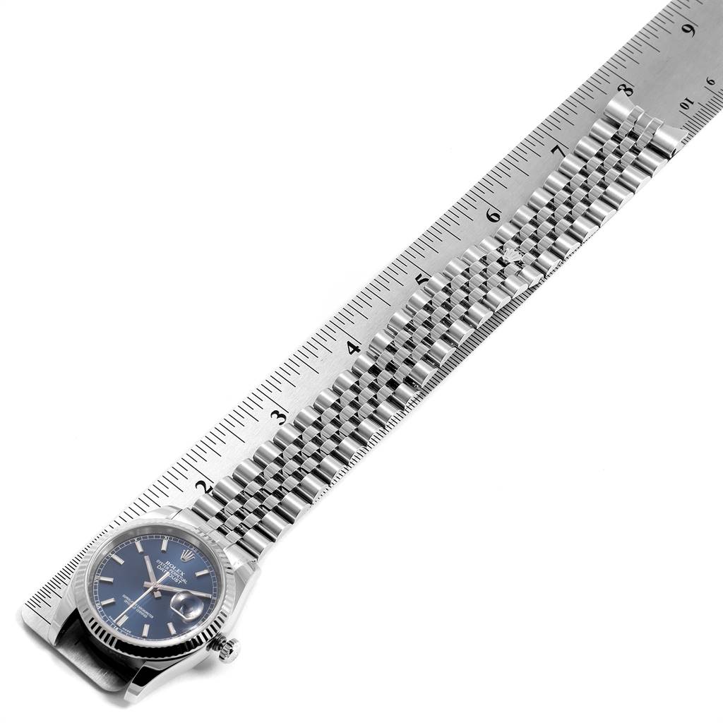 The Rolex Datejust 116234 Men's Stainless Steel Blue Dial 116234 Men's Stainless Steel Blue Dial watch is shown at an angle, highlighting its face, bezel, and metal strap against a ruler.