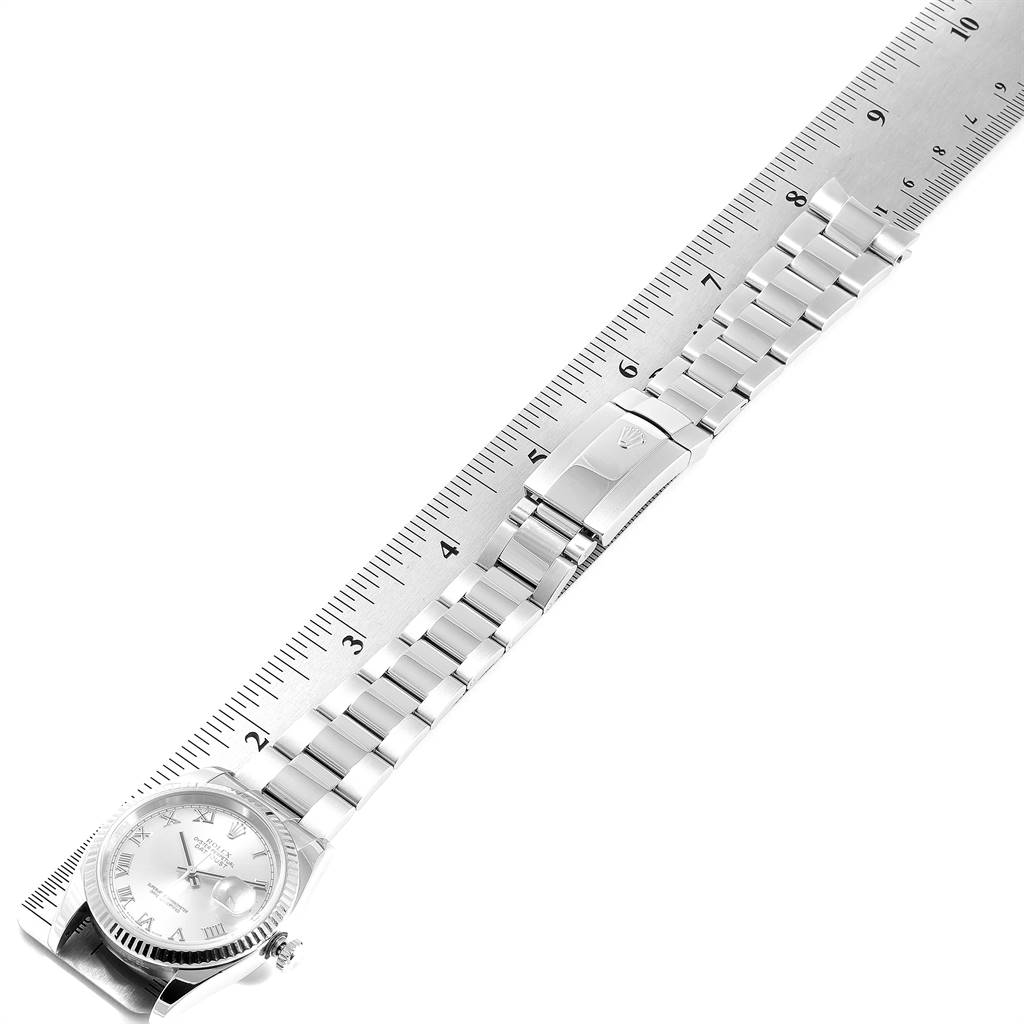 This Rolex Datejust 116234 Men
s Stainless Steel Grey Dial 116234 Men
s Stainless Steel Grey Dial watch is shown from a top-down angle, highlighting the bracelet and clasp next to a ruler.